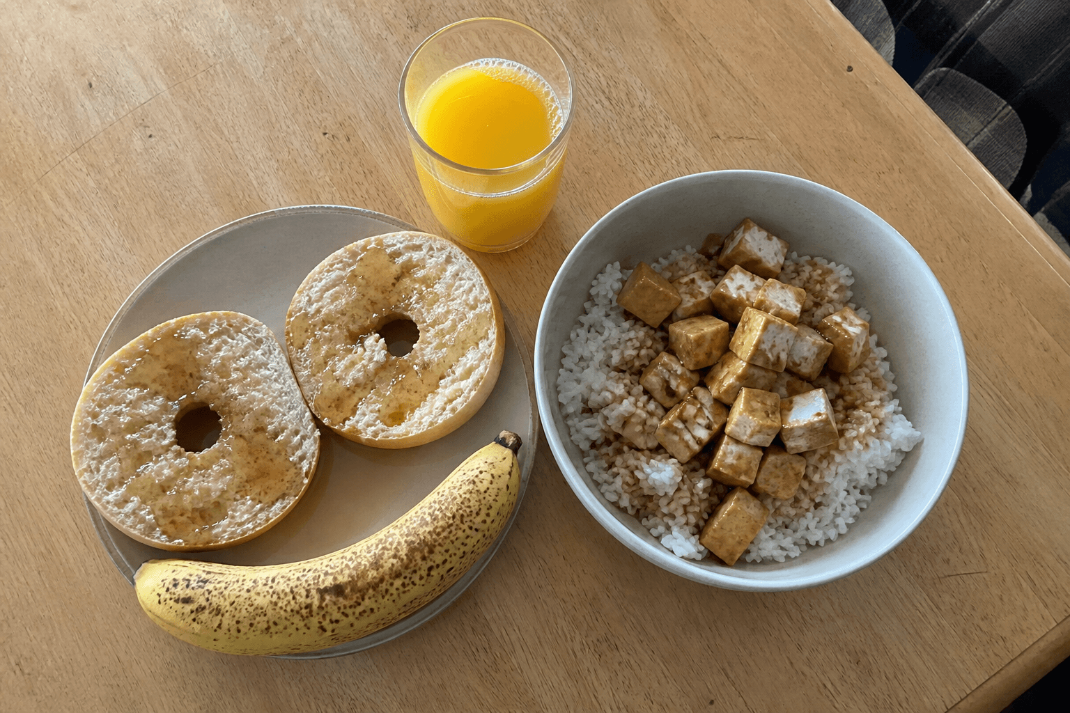 Low-fiber vegan carb loading breakfast of white bagel, banana, and maple syrup on a kitchen table, plantbaes.net